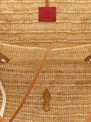Detailní pohled na tote tašku Christian Louboutin, zdůrazňující složitý proplet rafie a prvotřídní cervené kožené prošívání.