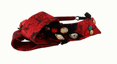 Gros plan sur le nœud artisanal en cristal et le logo DG ton or de l'accessoire pour cheveux en soie rouge cerise Dolce & Gabbana.