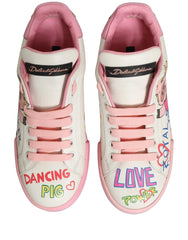Side profile of Dolce & Gabbana white leather sneakers with whimsical pink pig illustrations and black logo lettering.