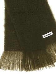 תקריב על צעיף הצמר של Jil Sander המציג את מבנה הסריגה המעודן ואת תווית הלוגו של המעצב התפורה בדיסקרטיות.