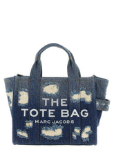 Marc Jacobs blue cotton canvas tote bag featuring bold white branding and structured top handles in a front view.