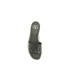 Nærbilde av premium kalveskinntekstur og polert gullfarget VLogo-emblem på Valentino Garavani-sandaler.