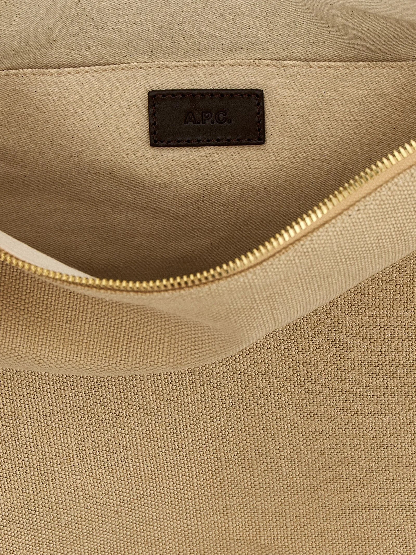 Detail kabelky přes rameno A.P.C., odhalující prémiové bavlněné tkaní a decentní logo.