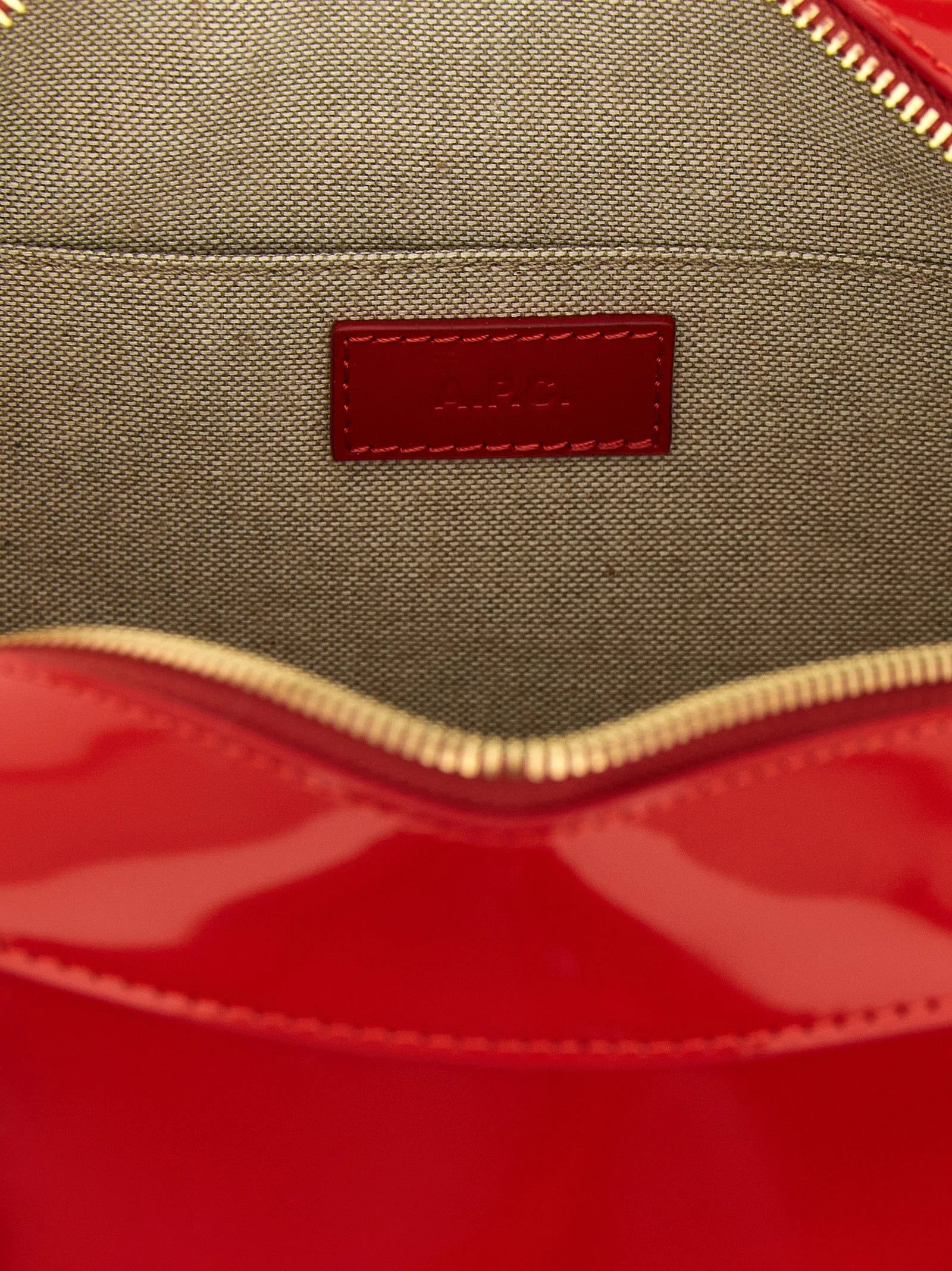 Dettaglio ravvicinato della borsa A.P.C. che illustra la texture della pelle di mucca di pregio e il discreto rilievo del logo in metallo dorato.