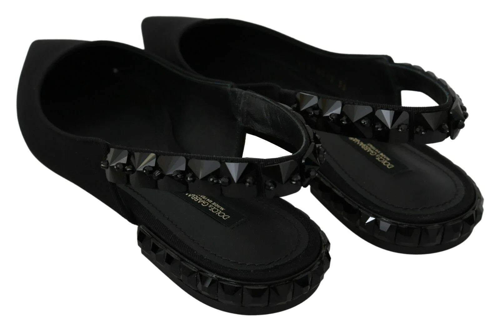 Gros plan de la texture luxueuse du tissu en soie charmeuse noire sur le bout pointu des chaussures plates Dolce & Gabbana.
