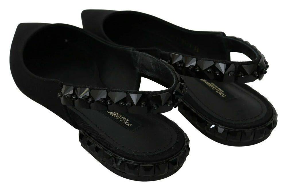 Gros plan de la texture luxueuse du tissu en soie charmeuse noire sur le bout pointu des chaussures plates Dolce & Gabbana.