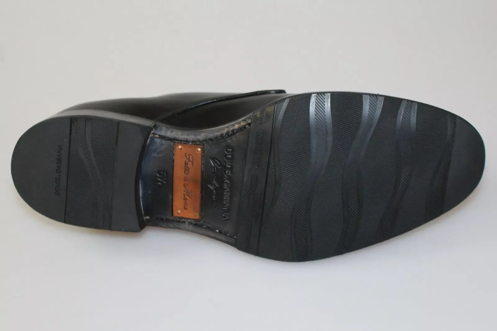 Macro view of the fine-grain black leather texture and tonal stitching on these hand-made Italian formal shoes.