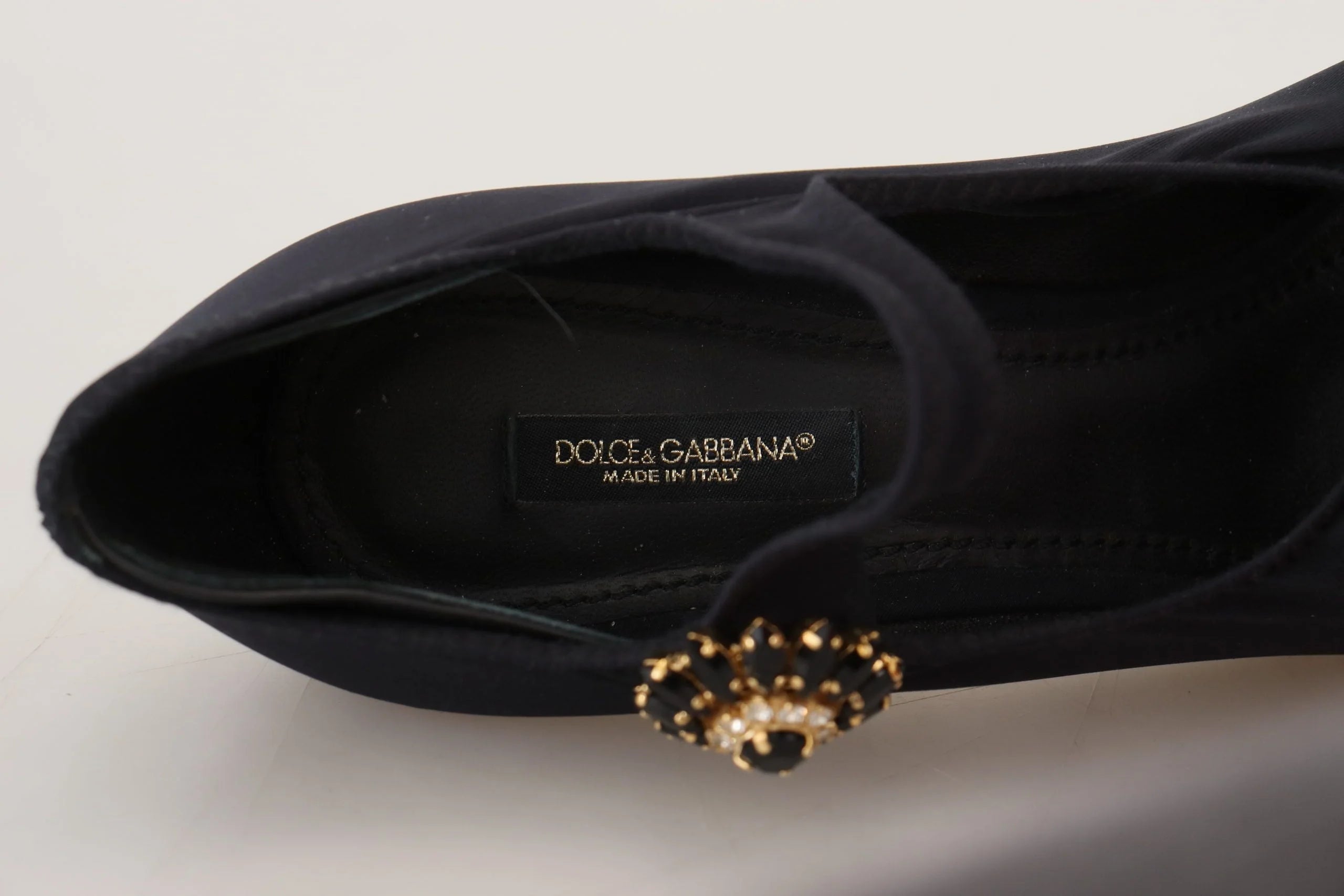 Dolce & Gabbanas sorte krystalsok-pumper præsenteret i et studie, der fremhæver det raffinerede aftenlook.