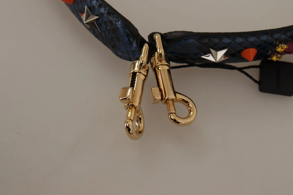 Yksityiskohta kiillotetusta kullansävyisestä lukkosoljesta, johon on kaiverrettu Dolce & Gabbana -logo sinisessä python-nahassa.