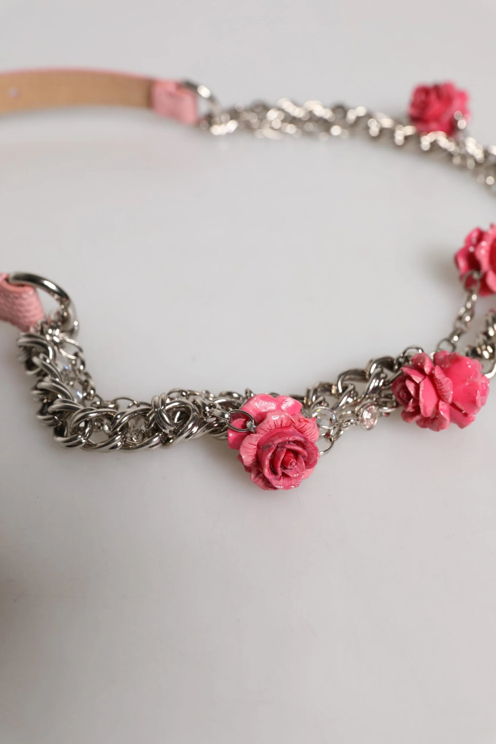 Close-up of the intricate brass and resin rose floral accents on the Dolce & Gabbana luxury leather belt.
