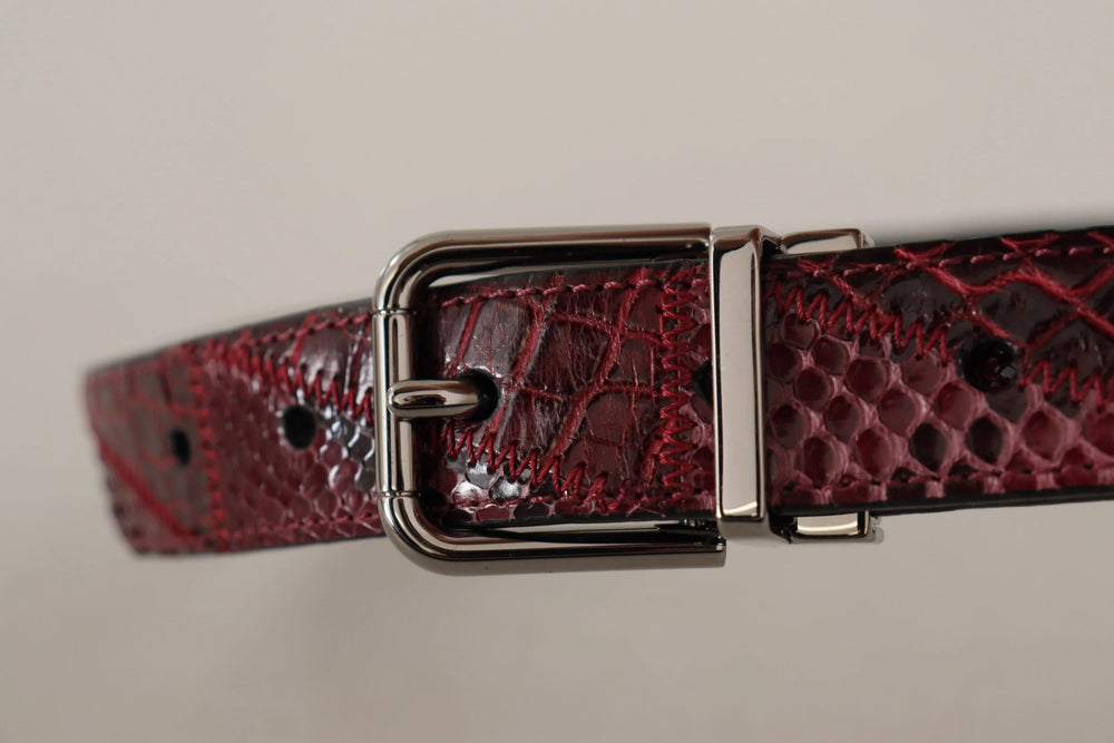 Detailní záběr na ikonické zlaté logo DG na červeném pythoním pásku, odrážející řemeslnou zručnost Dolce & Gabbana.