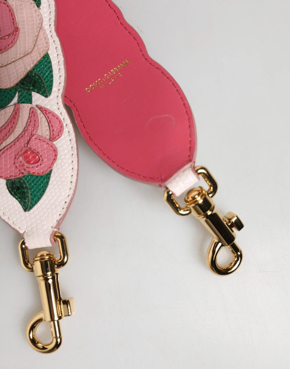 Közelkép a bonyolult virágmintáról és a rétegelt bőr részletekről a Dolce & Gabbana luxus táskapánton.