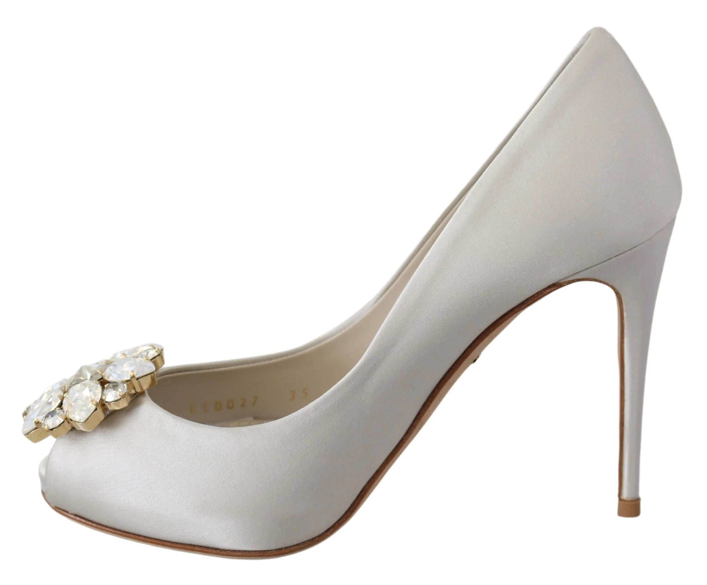 Vinklet billede af de krystaldetaljerede pumps fra Dolce & Gabbana, der viser den skinnende hvide satin og aften silhuet.