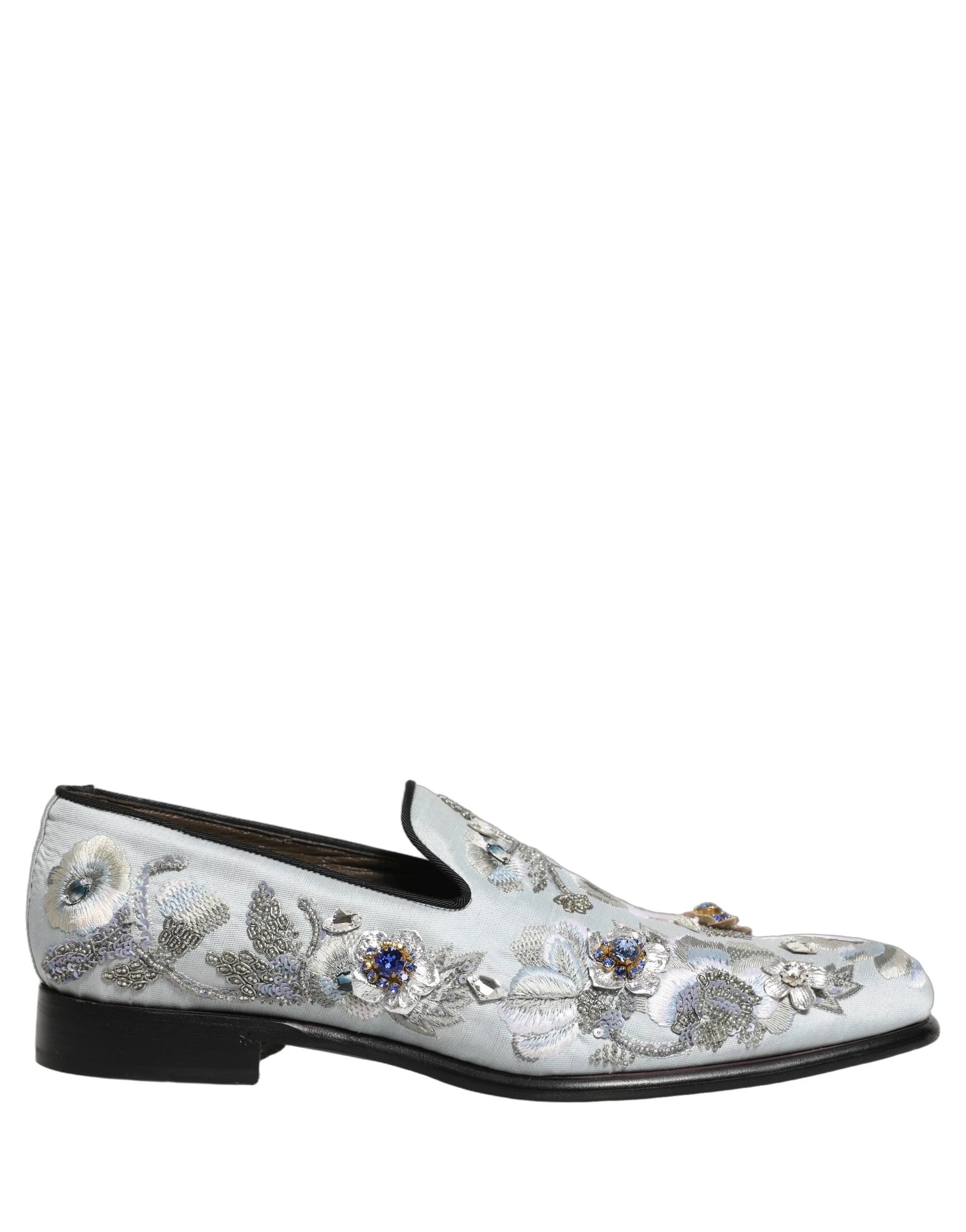 Ett par Dolce & Gabbana loafers i vitt med blommigt broderi, presenterade i en studio för en förfinad estetik.