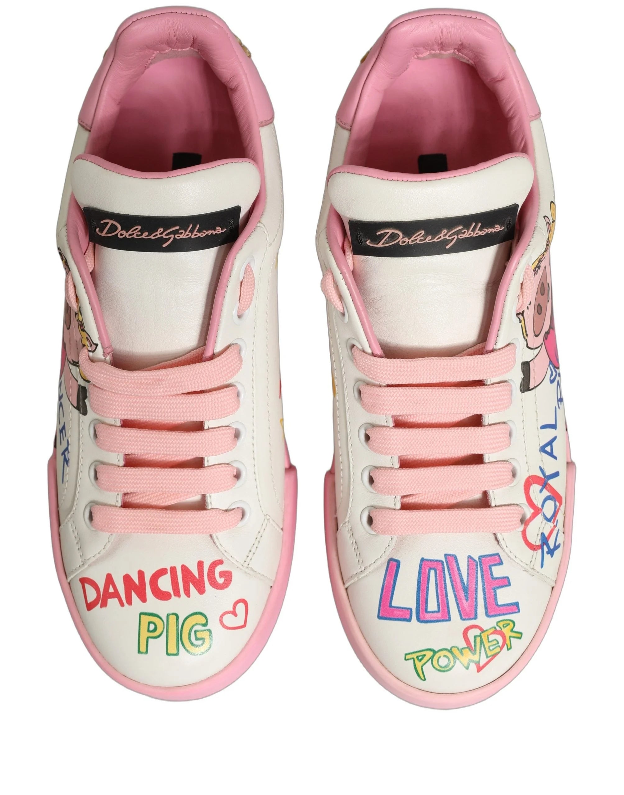 Side profile of Dolce & Gabbana white leather sneakers with whimsical pink pig illustrations and black logo lettering.