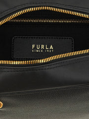 Detalhe close-up da mala Furla, mostrando a grão de couro de bezerro premium e o fecho metálico polido com o logótipo.