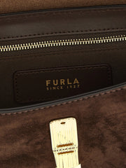 Detailní pohled na gravírování loga Furla a jemnou strukturu prémiové hnědé hovězí kůže.