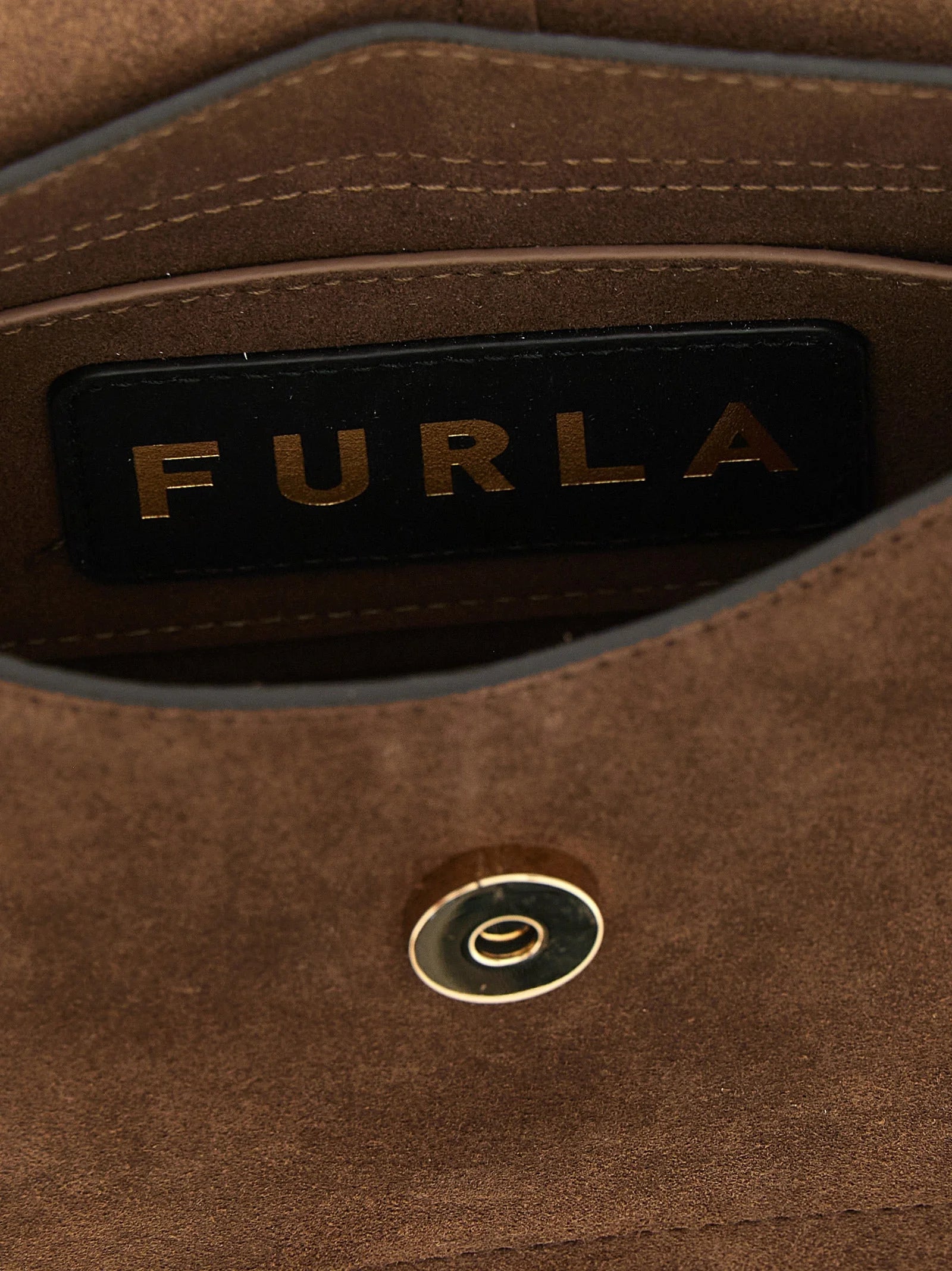 Detailní pohled na brown kabelku Furla s prvotřídní zrnitostí teletiny kůže a lešteným kovovým logem.