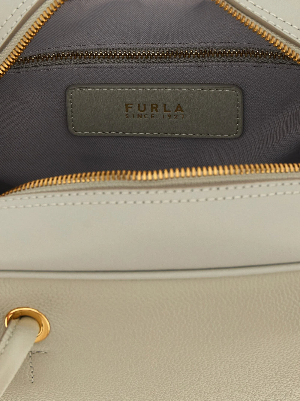 Zbliżenie na torebkę Furla w kolorze szarym, ukazujące drobne ziarno wysokiej jakości skóry cielęcej i polerowane elementy metalowe.