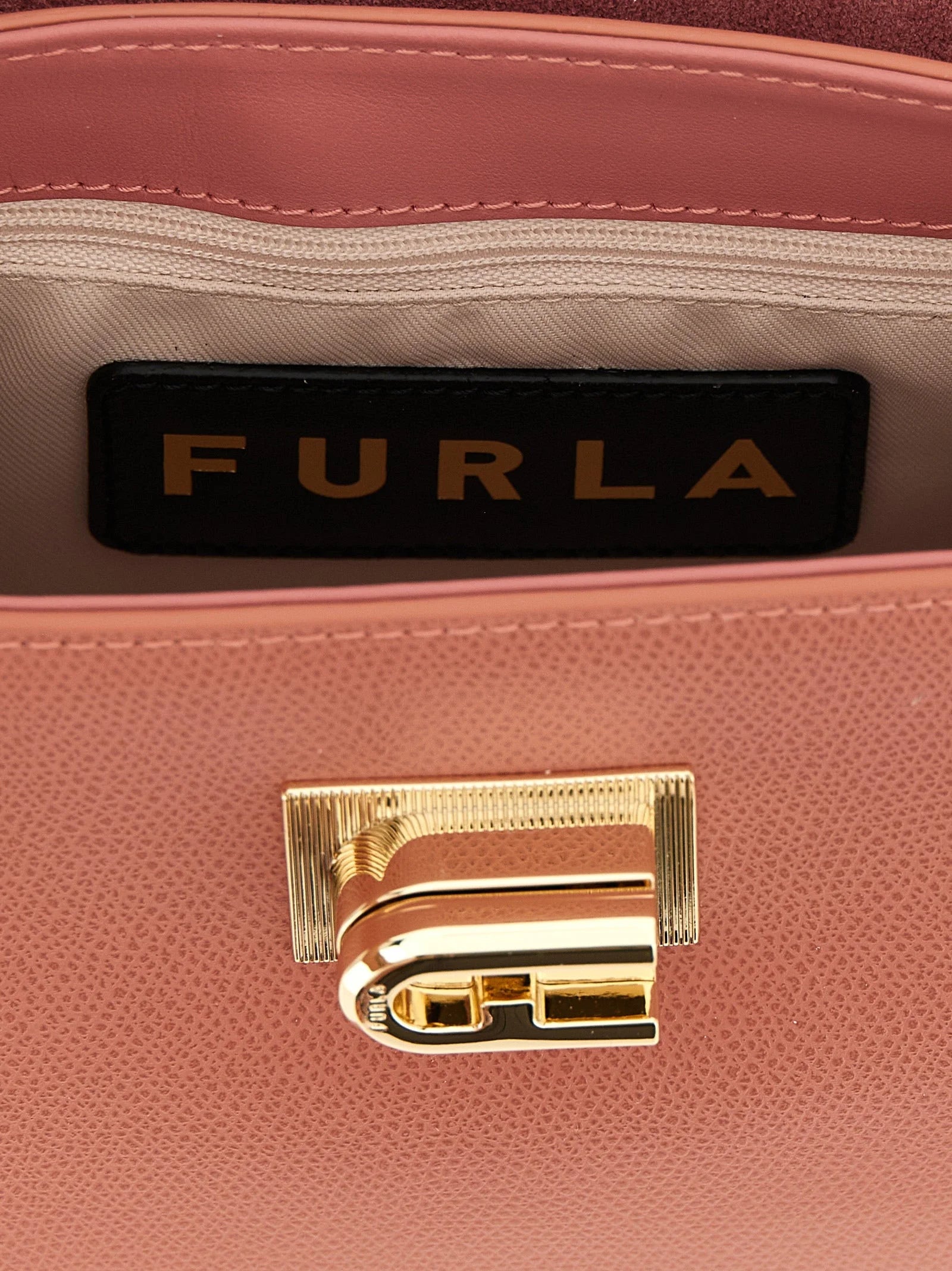 Apropiere de geanta Furla, dezvăluind granulația naturală a pielii de vițel și închizătorile metalice de precizie.