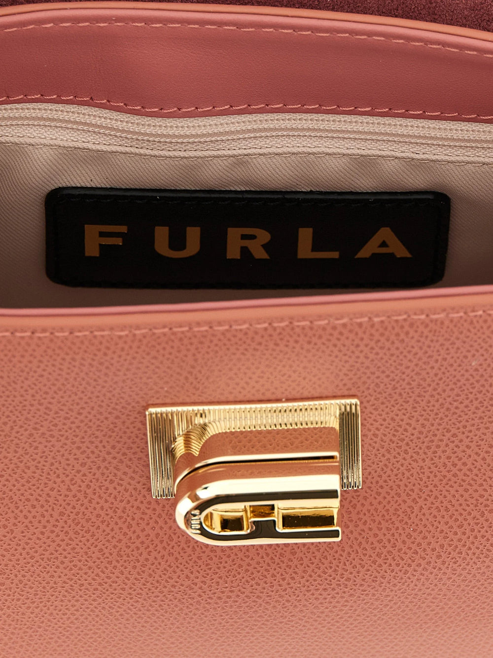 Apropiere de geanta Furla, dezvăluind granulația naturală a pielii de vițel și închizătorile metalice de precizie.