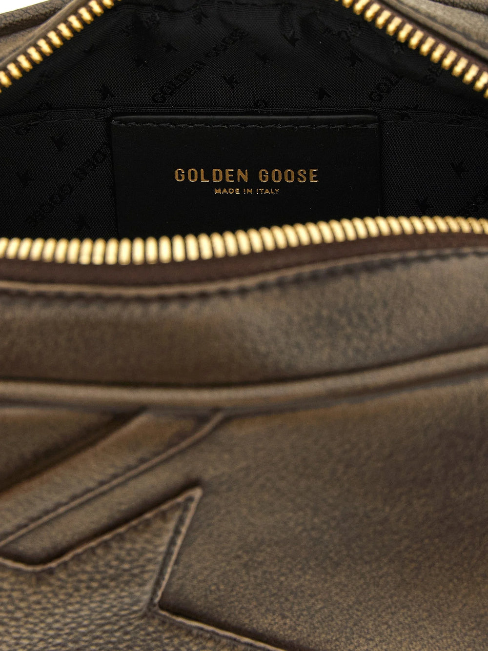 Close-up da clutch da Golden Goose revelando a textura rica da pele de vaca castanha e a costura tonal precisa.