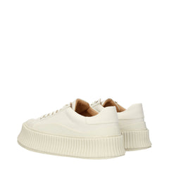 Närbild på Jil Sanders vita tyg sneakers med fokus på silverfärgade ögletter och premium bomullscanvasstruktur.