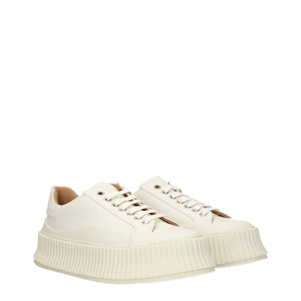 Sidoprofil av Jil Sanders vita canvassneakers som visar den upphöjda plattforms mellan sålen och rena ton-i-ton sömnaden.