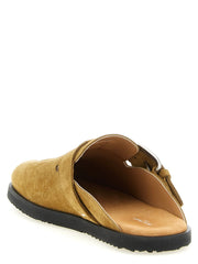 Baggrundsbillede af Maison Margiela brune slippers, der fremhæver det signerede hvide stiksøm på hælen.