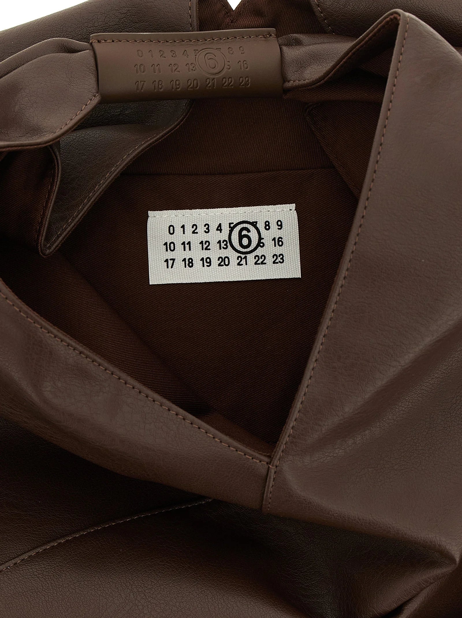 Gros plan de la texture du sac MM6 Maison Margiela et du détail de la poignée, mettant en valeur le savoir-faire raffiné du polyéthylène.