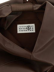 Gros plan de la texture du sac MM6 Maison Margiela et du détail de la poignée, mettant en valeur le savoir-faire raffiné du polyéthylène.