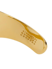 Close-up of the MM6 Maison Margiela gold bracelet highlighting the refined metallic finish and interior branding.