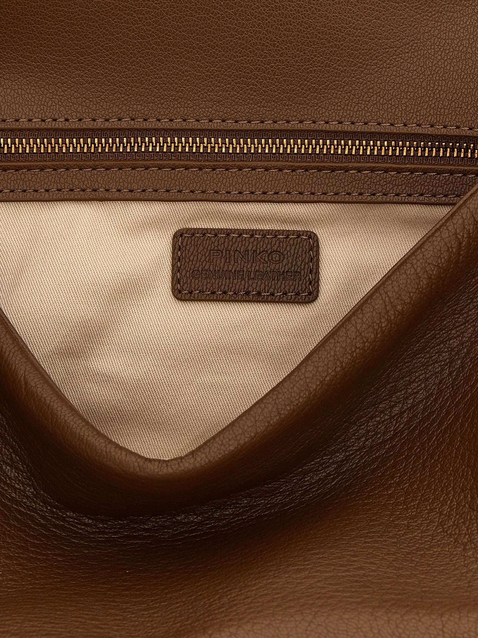Detailny pohľad na zlatú kovovú sponu PINKO a zrnitosť kože, ktorá ukazuje rafinovanú zručnosť značky.