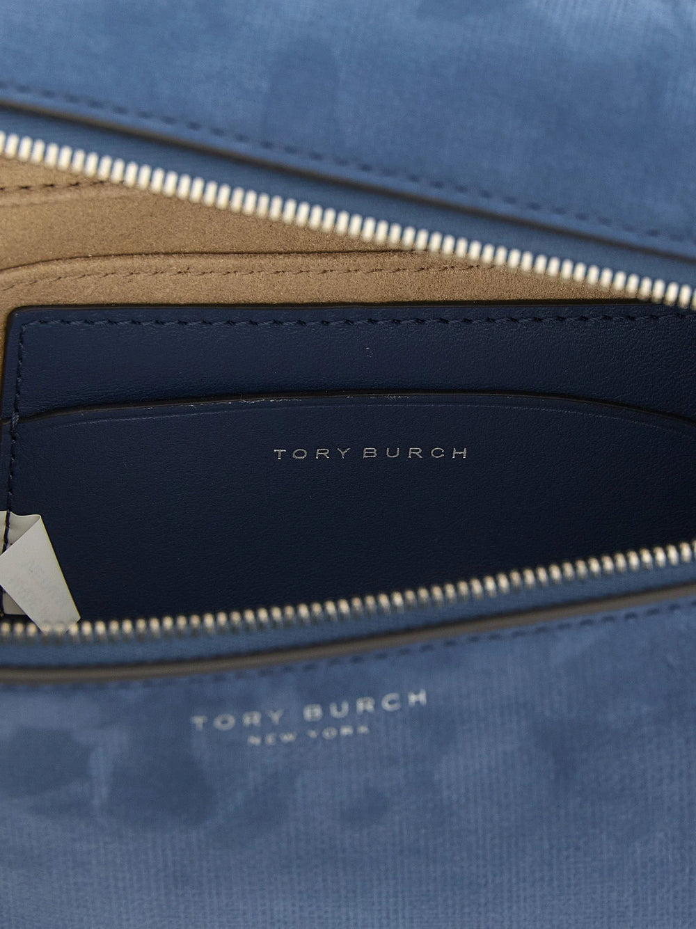 Tæt på Tory Burch blå taske, med fokus på det bløde lammeskind og den polerede metallogo-lukning.