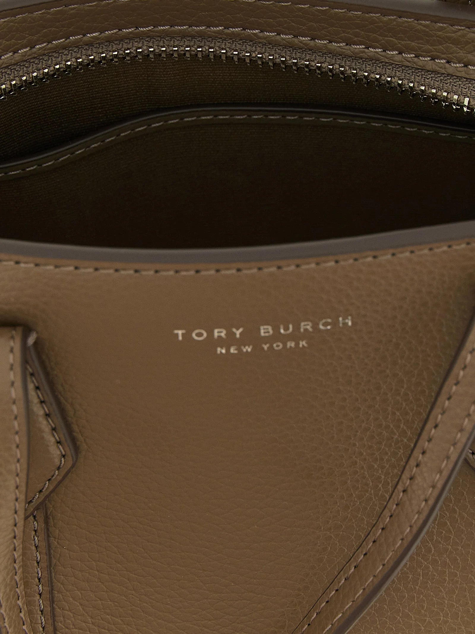 Primer plano del bolso tote de Tory Burch que muestra la veta natural del cuero de vaca marrón y los detalles precisos del hardware.