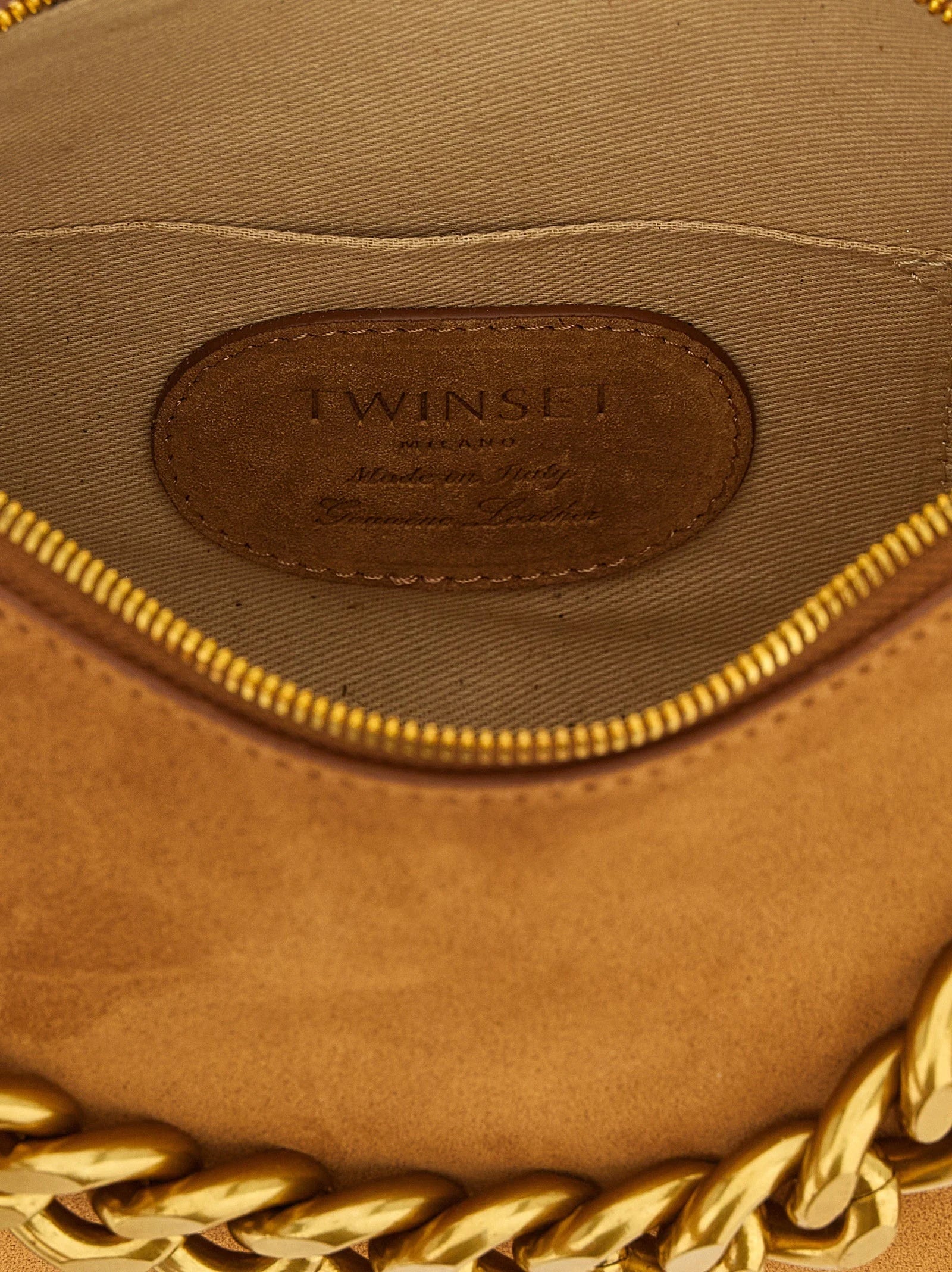 Dettaglio della texture in pelle marrone Twinset e del logo metallico lucido, che esalta l'artigianato ispirato all'Italia.