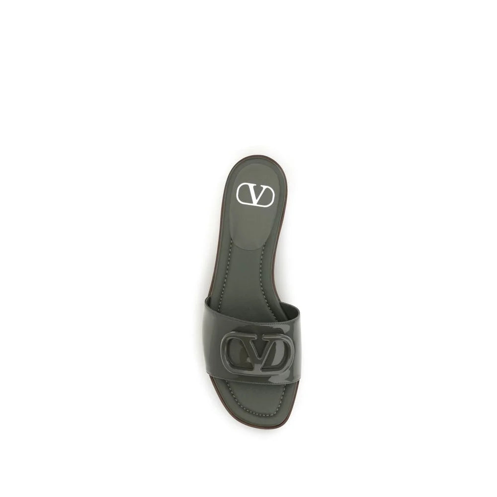 Nærbilde av premium kalveskinntekstur og polert gullfarget VLogo-emblem på Valentino Garavani-sandaler.
