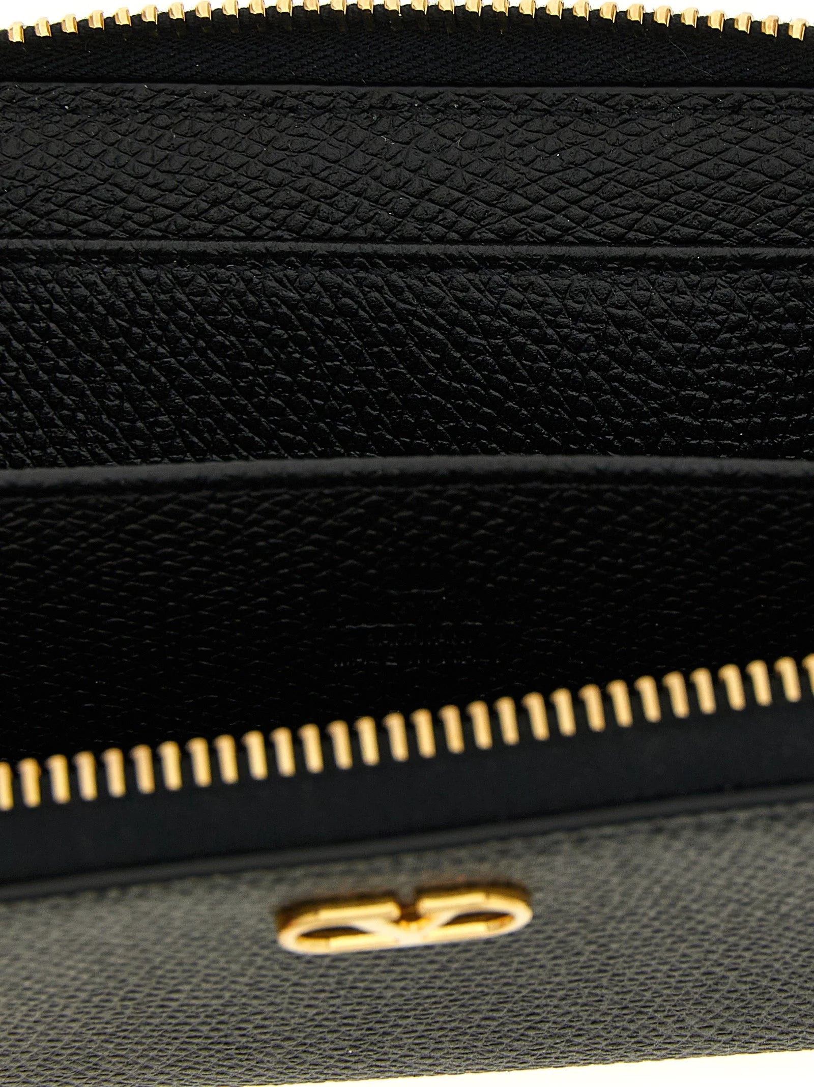 Close-up van het gladde zwarte rundleer en het gouden VLogo embleem op een Valentino Garavani luxe kaarthouder.