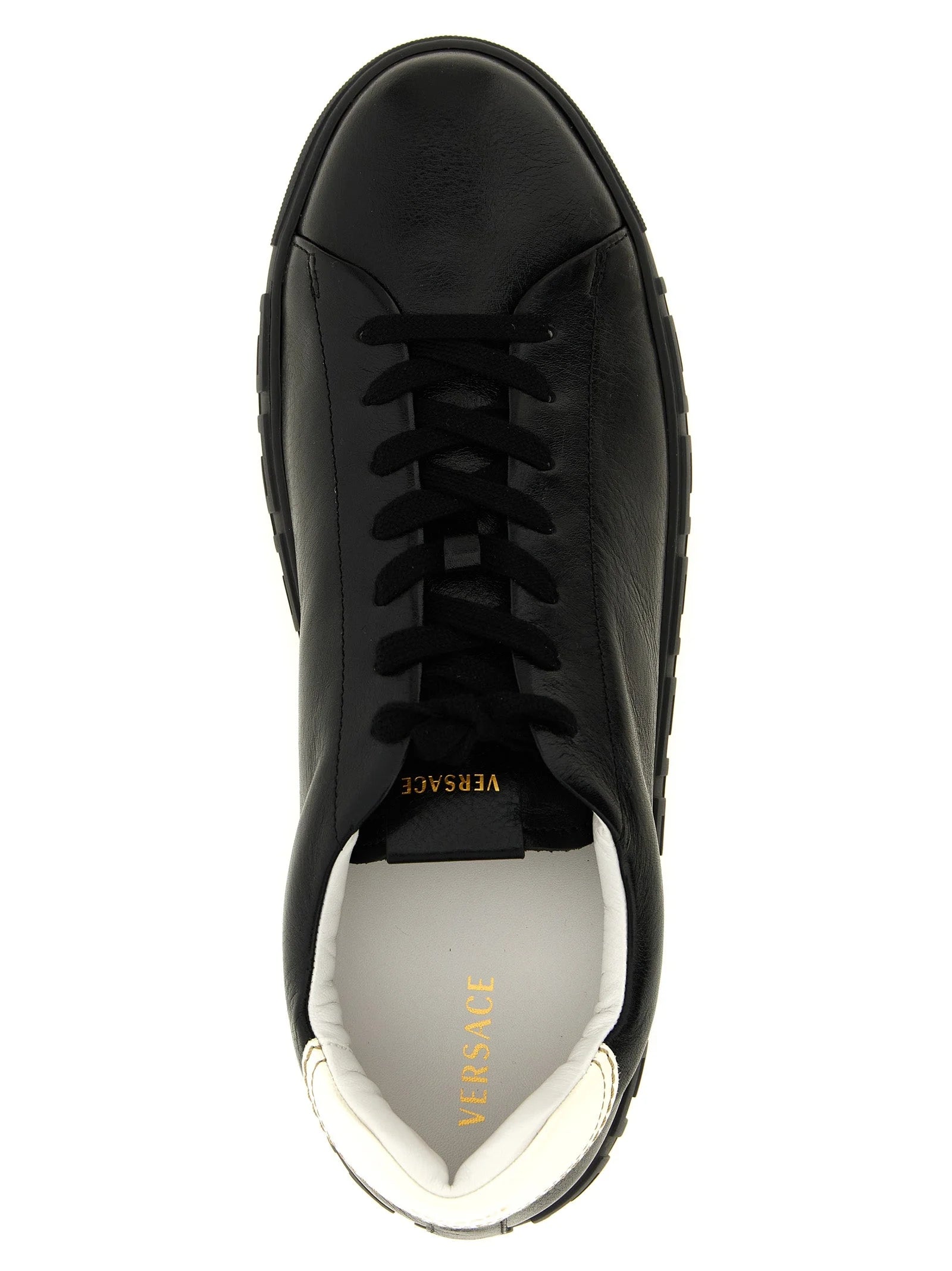 Zbliżenie na gładką fakturę skóry cielęcej i stonowane przeszycia w tych luksusowych, dwukolorowych sneakersach Versace.