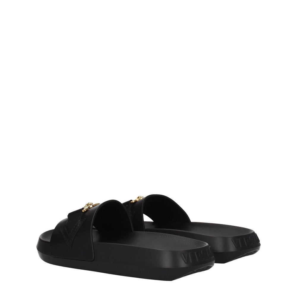 Detalle de cerca del grano de cuero negro flexible y la costura tonal precisa en las exclusivas sandalias de Versace.