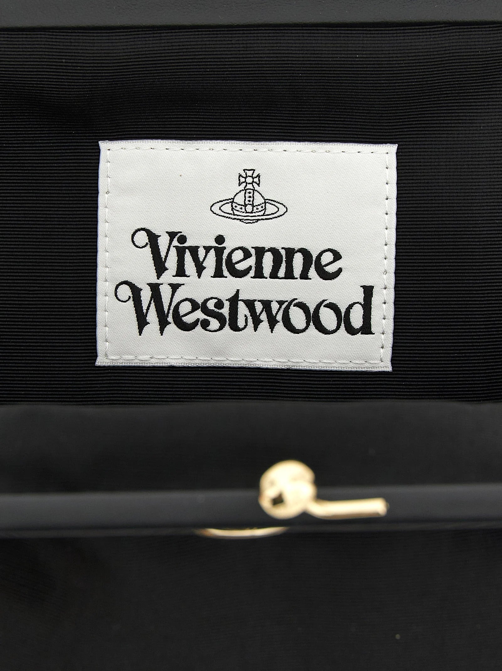 Detalle de cerca del interior del bolso clutch de Vivienne Westwood y el hardware de metal pulido, que muestra la artesanía de la marca.