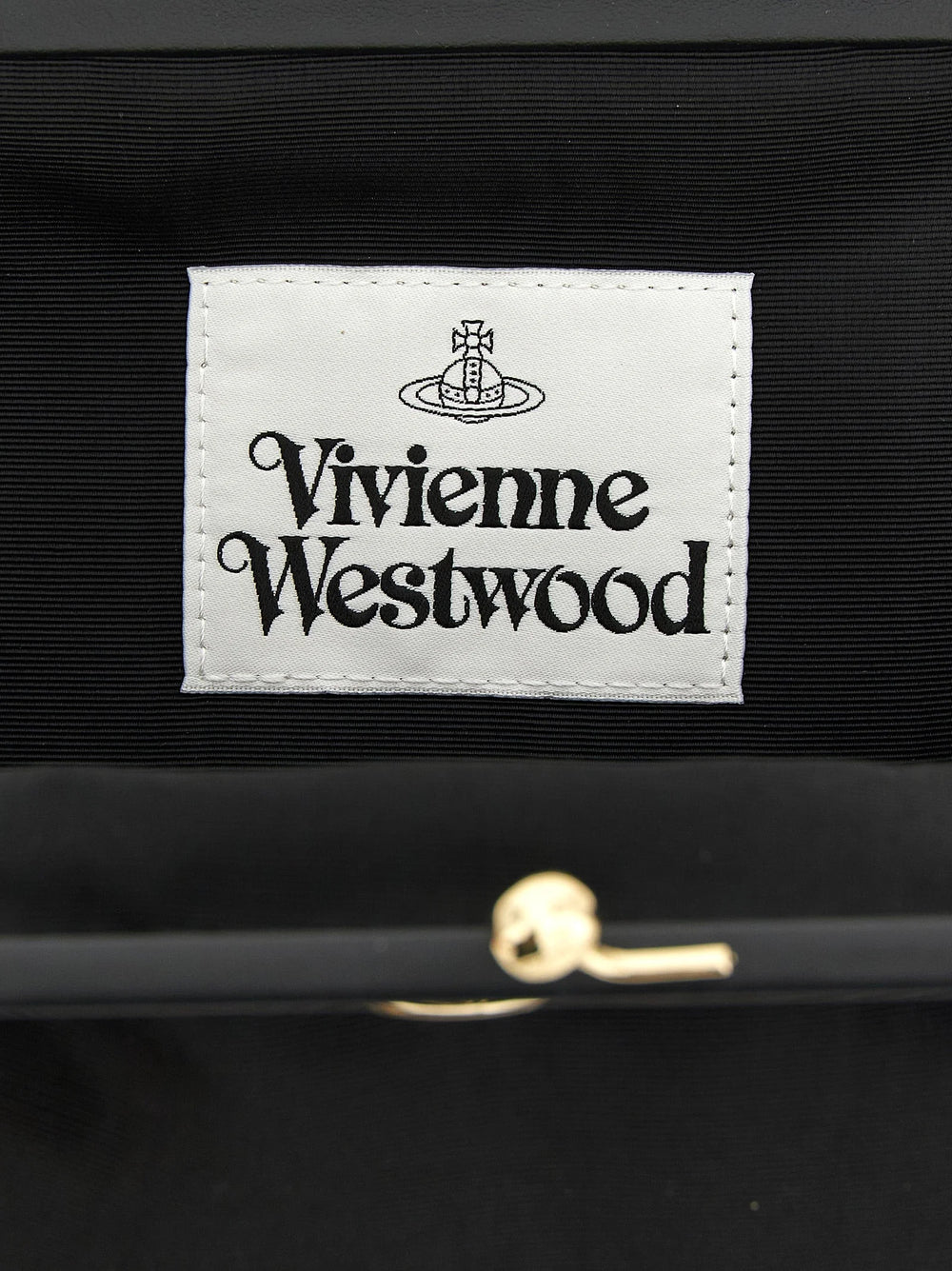 Detalle de cerca del interior del bolso clutch de Vivienne Westwood y el hardware de metal pulido, que muestra la artesanía de la marca.